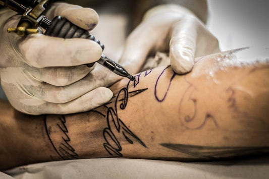 An tattoo artist use coil machine to tattoo a client.