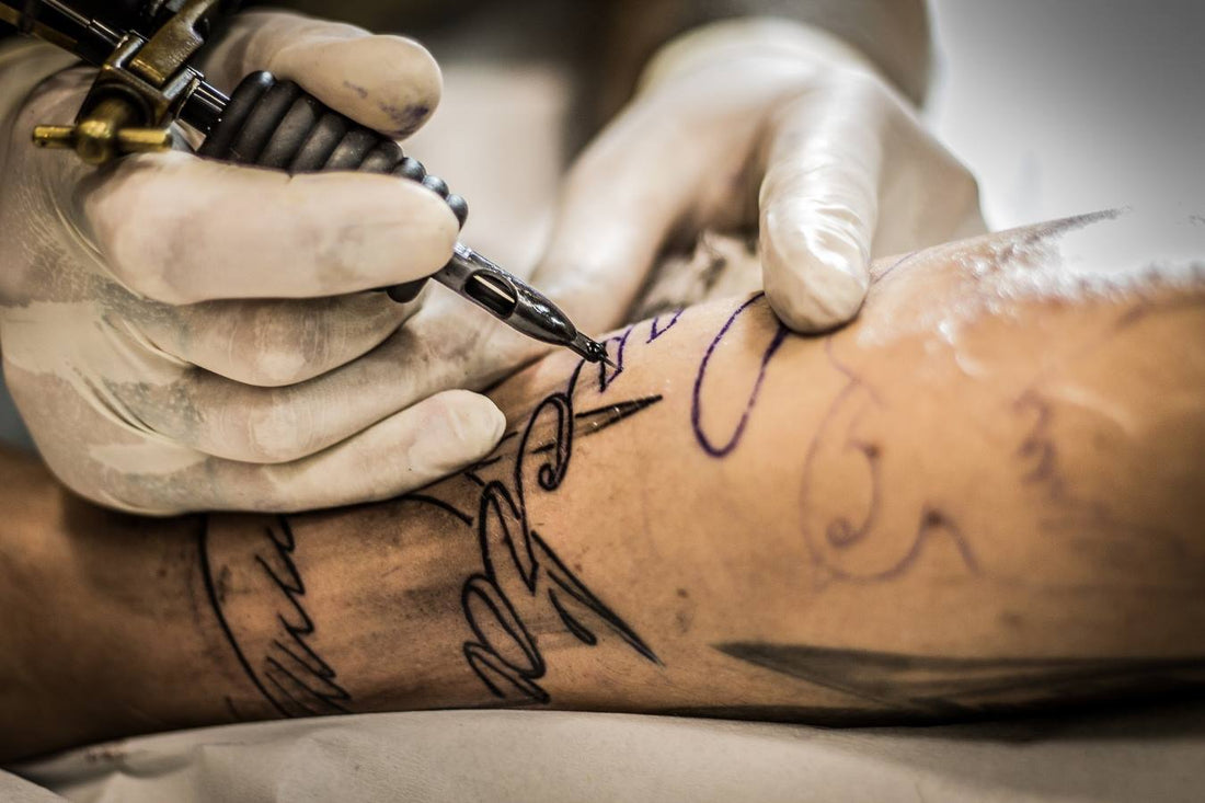 An tattoo artist use coil machine to tattoo a client.