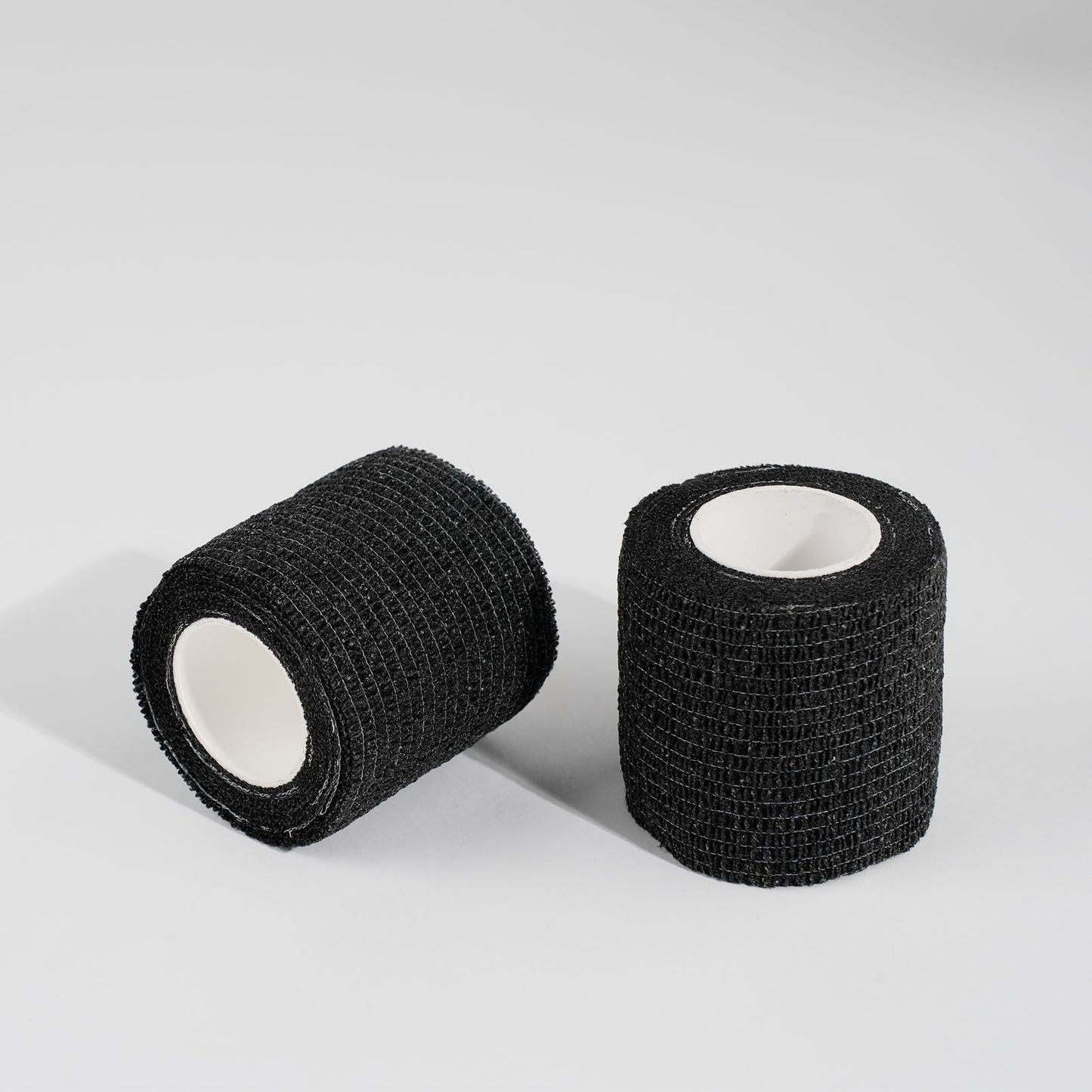 Black cohesive tattoo grip tape rolls for tattoo machines, non-slip self-adhesive wrap for professional tattoo artists.