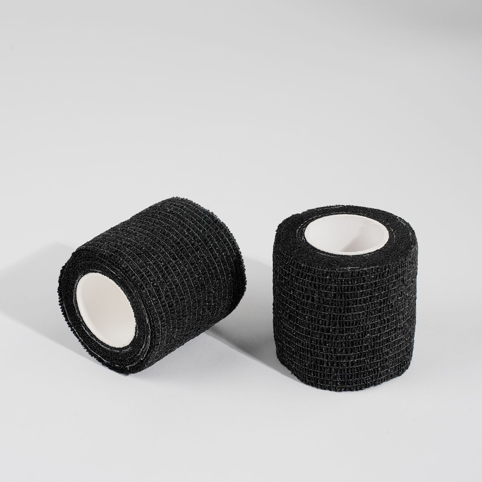 Black cohesive tattoo grip tape rolls for tattoo machines, non-slip self-adhesive wrap for professional tattoo artists.