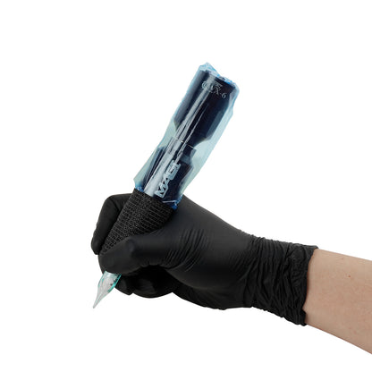 Tattoo artist hand wearing black glove holding MAGI rotary tattoo pen machine with WX-6 wireless battery, wrapped in protective cover and grip tape.