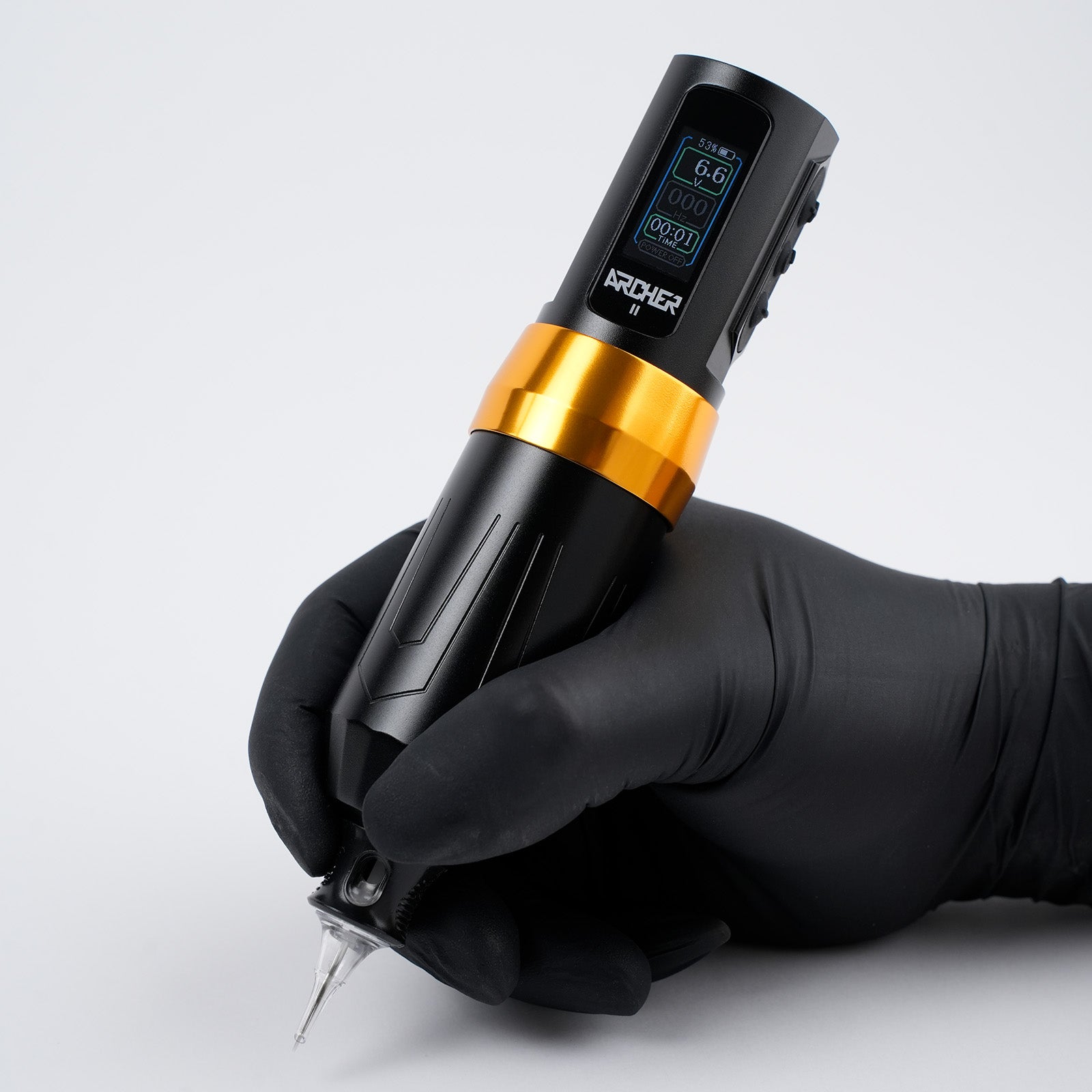 Tattoo artist wearing black nitrile glove holding the Dragoart Archer II wireless rotary tattoo pen machine with OLED display showing voltage and battery level.