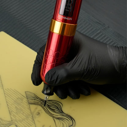 Artist using the Dragoart Hammer tattoo machine in red to create a tattoo design on practice skin, showcasing the machine's precision and ergonomic grip.